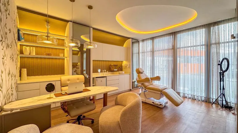 Sala clínica e estética de alto padrão com maca motorizada, foco cirúrgico, painéis de nogueira e estrutura para gravação de vídeo